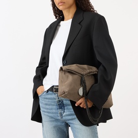 Model carrying Stella McCartney Falabella Medium Drawstring Tote Bag in dark taupe with black chain handles and engraved logo medallion