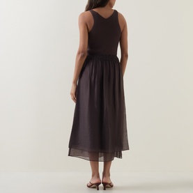Model wearing Vince brown midi dress, sleeveless with V-back bodice and sheer layered skirt, styled with flat mule sandals