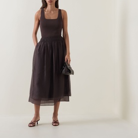 Model wearing Vince brown sleeveless midi dress with gathered skirt, styled with strappy heeled mules and small clutch bag.