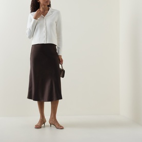 Model wearing Vince off white wool cashmere knit top with dark brown midi skirt, small black bag and nude kitten heels.