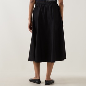 Model wearing Vince black cotton midi skirt, rear view, with black ballet flats. Full A-line silhouette with elasticated waistband.