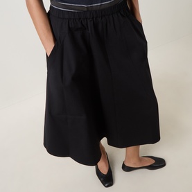 Model wearing Vince black midi skirt with elasticated waist and front pockets, styled with black ballet flats