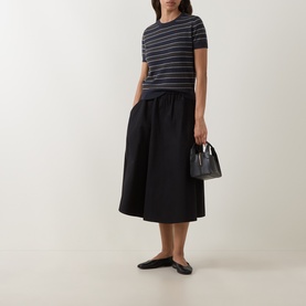 Model wearing Vince black cotton midi skirt with gathered waist, styled with striped tee, black mini bag and flat ballet shoes.