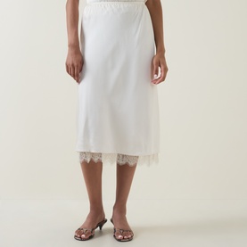 Model wearing Vince cream slip midi skirt with lace hem trim, styled with silver strappy heeled mules.
