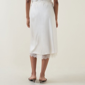 Model wearing Vince cream viscose midi skirt with lace hem trim, styled with black kitten heel mules. Rear view.