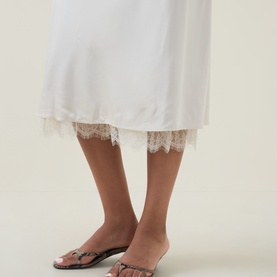 Model wearing Vince cream slip skirt with lace hem trim, styled with embellished flat mule sandals