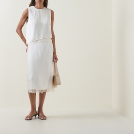 Model wearing Vince cream viscose midi skirt with lace hem trim, styled with matching sleeveless top, small bag and silver heels.
