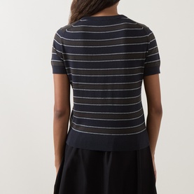 Model wearing Vince T-Shirt in Thyme Combo, back view, fine knit stripe short-sleeve top, styled with black midi skirt.