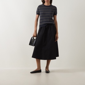 Model wearing Vince Thyme Combo striped cotton-cashmere T-shirt, styled with black midi skirt, flat shoes and small structured bag.