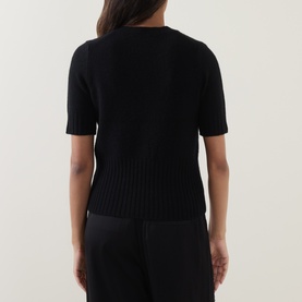 Model wearing Vince black wool-cashmere blend short-sleeve knit top, ribbed hem detail, back view. Styled with black trousers.