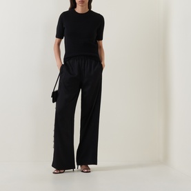 Model wearing Vince black wool-cashmere short-sleeve top with wide-leg black trousers and black heeled sandals.