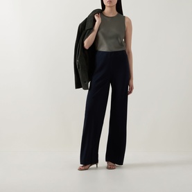Model wearing Vince navy wide-leg trousers in Naia&trade; acetate blend, styled with khaki sleeveless top and blazer draped over shoulder.