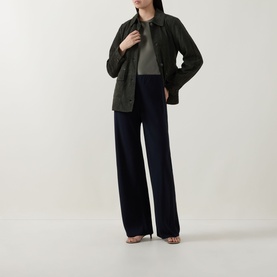 Model wearing Vince top in Pine Grove, styled with dark olive jacket and wide-leg navy trousers, strappy heeled sandals.