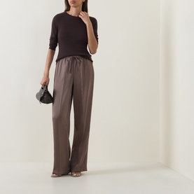 Model wearing Vince top in Taupe Haze cotton, styled with wide-leg trousers and strappy heels, carrying a small black bag.