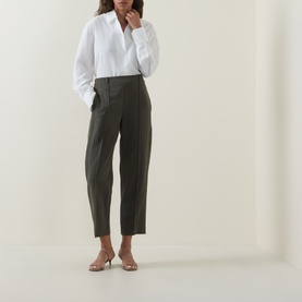 Model wearing Vince trousers in Sea Vine, tapered leg with front pleats, styled with a white shirt and nude heeled mules.