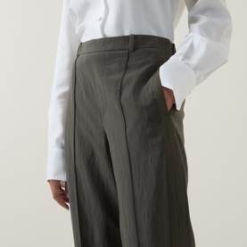 Model wearing Vince trousers in Sea Vine, wide-leg silhouette with front pleats and belt loops, styled with a white shirt.