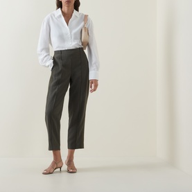 Model wearing Vince sea vine tailored trousers with white shirt and nude heeled mules, carrying a cream bag.