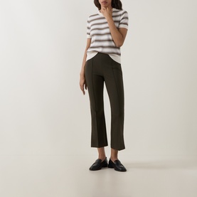 Model wearing Vince khaki trousers, styled with a white striped tee and black loafers