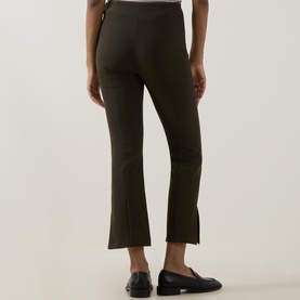 Model wearing Vince khaki cropped flared trousers, styled with black leather loafers, rear view showing split hem detail.