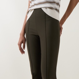 Model wearing Vince khaki trousers with front seam detail, styled with a striped white and brown T-shirt.