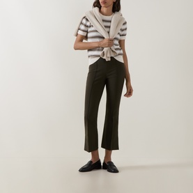 Model wearing Vince khaki trousers with a striped tee and white knitwear draped over shoulders, styled with black loafers.