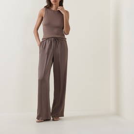 Model wearing Vince taupe haze wide-leg trousers with elasticated waist, styled with a matching sleeveless top and strappy heels.