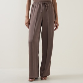 Model wearing Vince taupe haze wide-leg trousers with elasticated drawstring waist, styled with tan strappy heeled sandals.