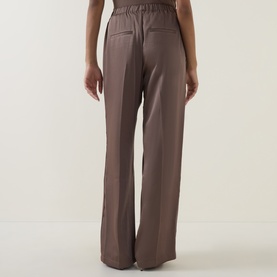 Model wearing Vince taupe haze wide-leg trousers, rear view, featuring elasticated waistband and relaxed straight fit.