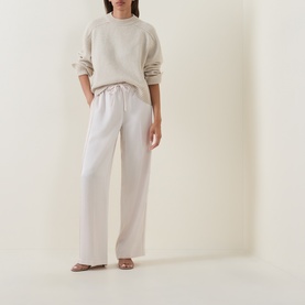 Model wearing Vince trousers in Blush Cloud, wide-leg silhouette with elasticated waist, styled with a cream sweatshirt and strappy sandals.