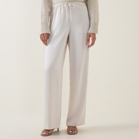 Model wearing Vince Blush Cloud wide-leg drawstring trousers, styled with a cream knit top and nude heeled mules.