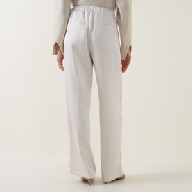 Model wearing Vince blush cloud wide-leg trousers, rear view, with elasticated waist, styled with a beige top.