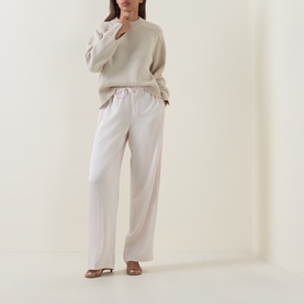 Model wearing Vince trousers in Blush Cloud, wide-leg silhouette with elasticated waist, styled with a cream knit jumper and nude heels.