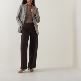 Model wearing Vince Pleated Straight-Leg Trousers in brown with pressed pleats, styled with a grey blazer and beige top.