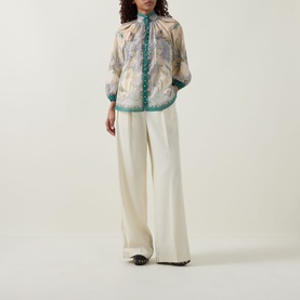Model wearing Zimmermann Indra Billow Scarf Floral Blouse in Cream Scarf Floral with teal trim, styled with wide-leg cream trousers.