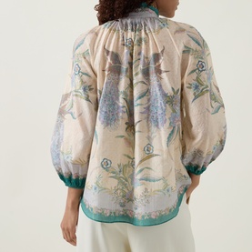 Model wearing Zimmermann Indra Billow Scarf Floral Blouse in Cream Scarf Floral, showing back view with balloon sleeves and teal trim cuffs.