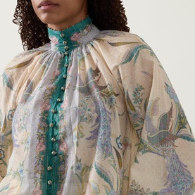 Model wearing Zimmermann Indra Billow Scarf Floral Blouse in Cream Scarf Floral, featuring teal stand collar, gold bead trim and enamel button placket