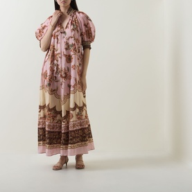 Model wearing Zimmermann dress in Mauve Jacobean, floral print with puff sleeves and tiered maxi length, styled with strappy heeled sandals