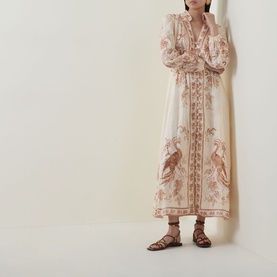 Model wearing Zimmermann Indra Linen Plunge Dress in Cream Tan Floral with peacock print, midi length, styled with brown strappy flat sandals.