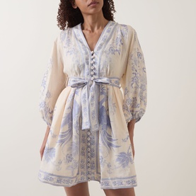 Model wearing Zimmermann dress in Cream Lilac Floral, featuring balloon sleeves, button-front detail, and tie waist, mini length.
