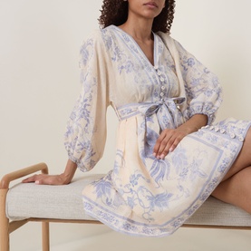 Model wearing Zimmermann dress in cream lilac floral, featuring balloon sleeves, V-neckline, button front, and tied waist belt