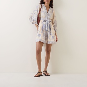 Model wearing Zimmermann Cream Lilac Floral mini dress with balloon sleeves and tie waist, styled with flat sandals and brown bag
