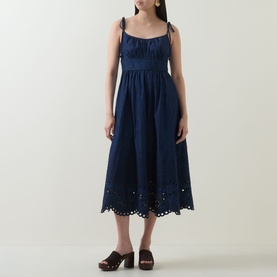 Model wearing Zimmermann ink blue broderie anglaise midi dress with tie shoulders, paired with brown mule heels.