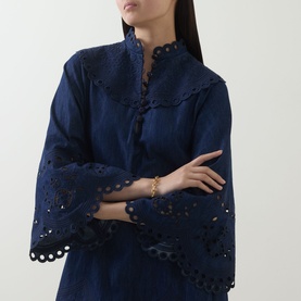 Model wearing Zimmermann ink blue broderie anglaise dress with mandarin collar and flared sleeves, styled with gold bracelet
