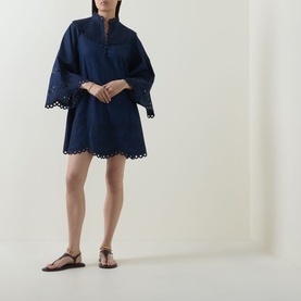 Model wearing Zimmermann ink mini dress with broderie anglaise hem and wide sleeves, styled with tan strappy flat sandals