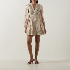 Model wearing Zimmermann Dress in Sage Tapestry Floral; long puff sleeves, V-neck, tiered mini skirt, styled with strappy heeled mules.