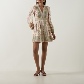 Model wearing Zimmermann Dress in Sage Tapestry Floral; long sleeves, V-neck, flared mini skirt, styled with strappy heeled sandals.