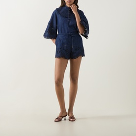 Model wearing Zimmermann blue cotton broderie anglaise shorts with matching top, flared sleeves, and tan heeled mules