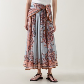 Model wearing Zimmermann skirt in Blue Paisley Floral silk, featuring wrap front, gathered waist, and midi length, styled with black strappy sandals.