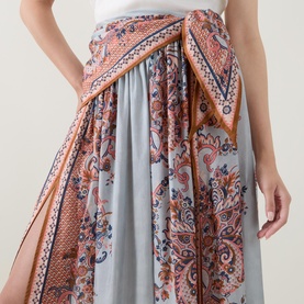 Model wearing Zimmermann silk skirt in Blue Paisley Floral, with wrap-style waist detail and gathered midi length.