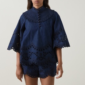 Model wearing Zimmermann blue cotton broderie anglaise top with scalloped hem and floral cutwork detail, styled with matching shorts